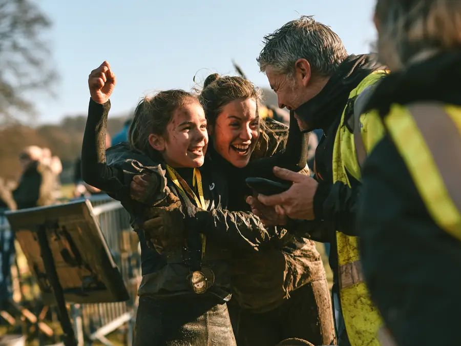 En ung deltagare med medalj jublar tillsammans med två andra efter målgång.